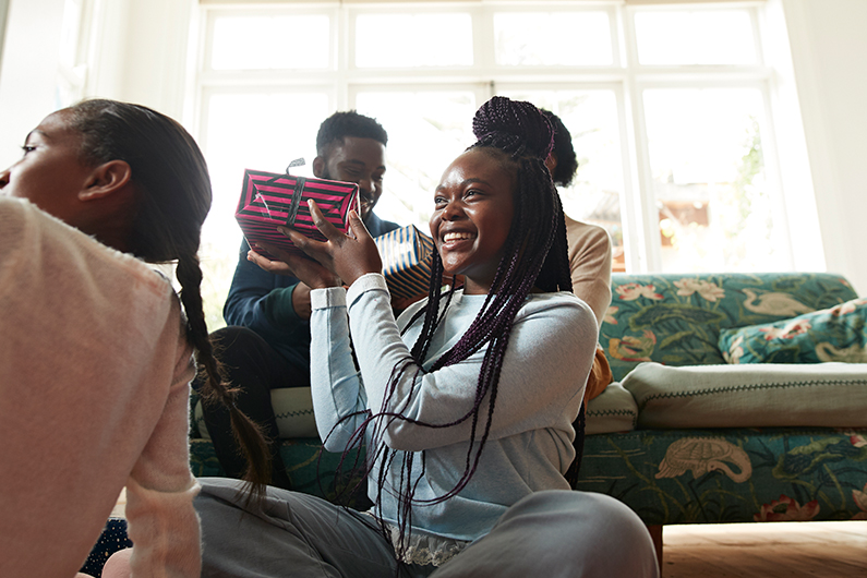 A young girl smiles while holding up a gift she received while spending time with family.