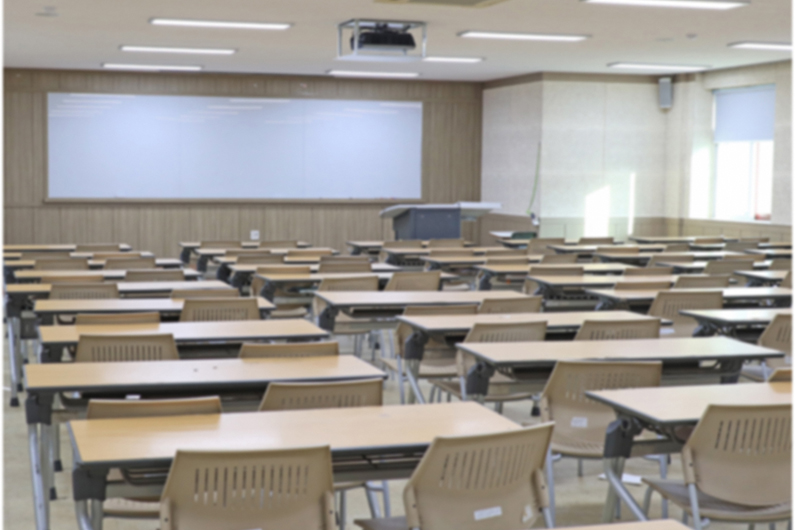 A classroom with desks and a large whiteboard in the front 