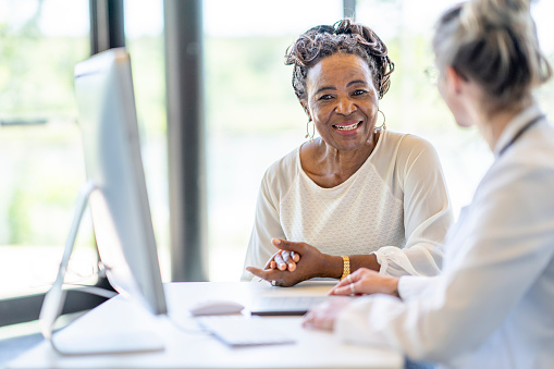 Women sitting down smilling looking at a computer with a medical professional