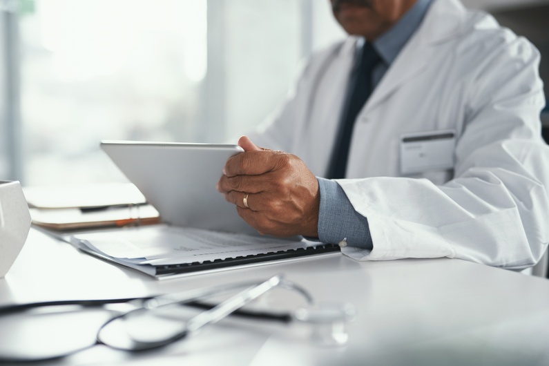 Shoulders and arms of medical professional working at a desk.