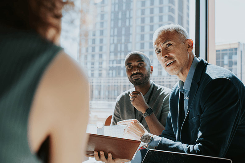 Group of 3 executives have a discussion about business cash reserves in a corporate office.