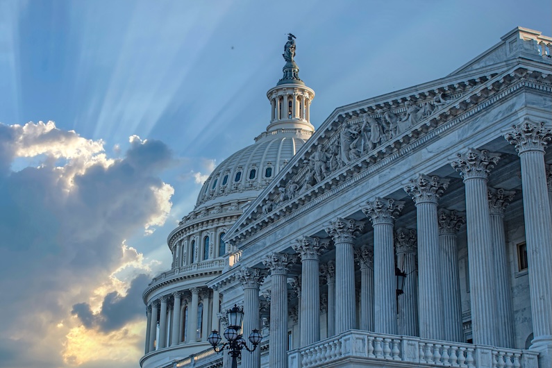 U.S. Capitol building with its iconic dome and columns under a dramatic sky in Washington, D.C.