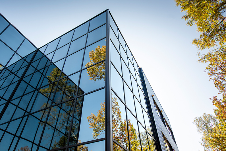 Exterior view of an office building with large reflective windows on a sunny day.