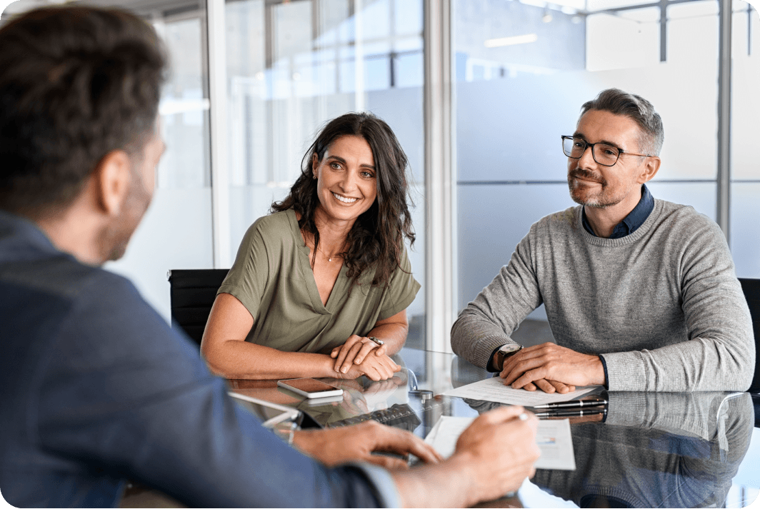 Three people sit at  table smiling and talking