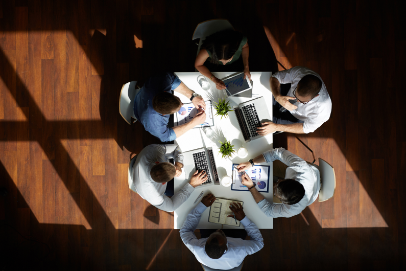 Overhead shot of a group of people having a meeting in a conference room with wooden floors
